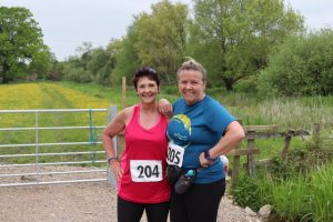 Two lady runners standing by a gate